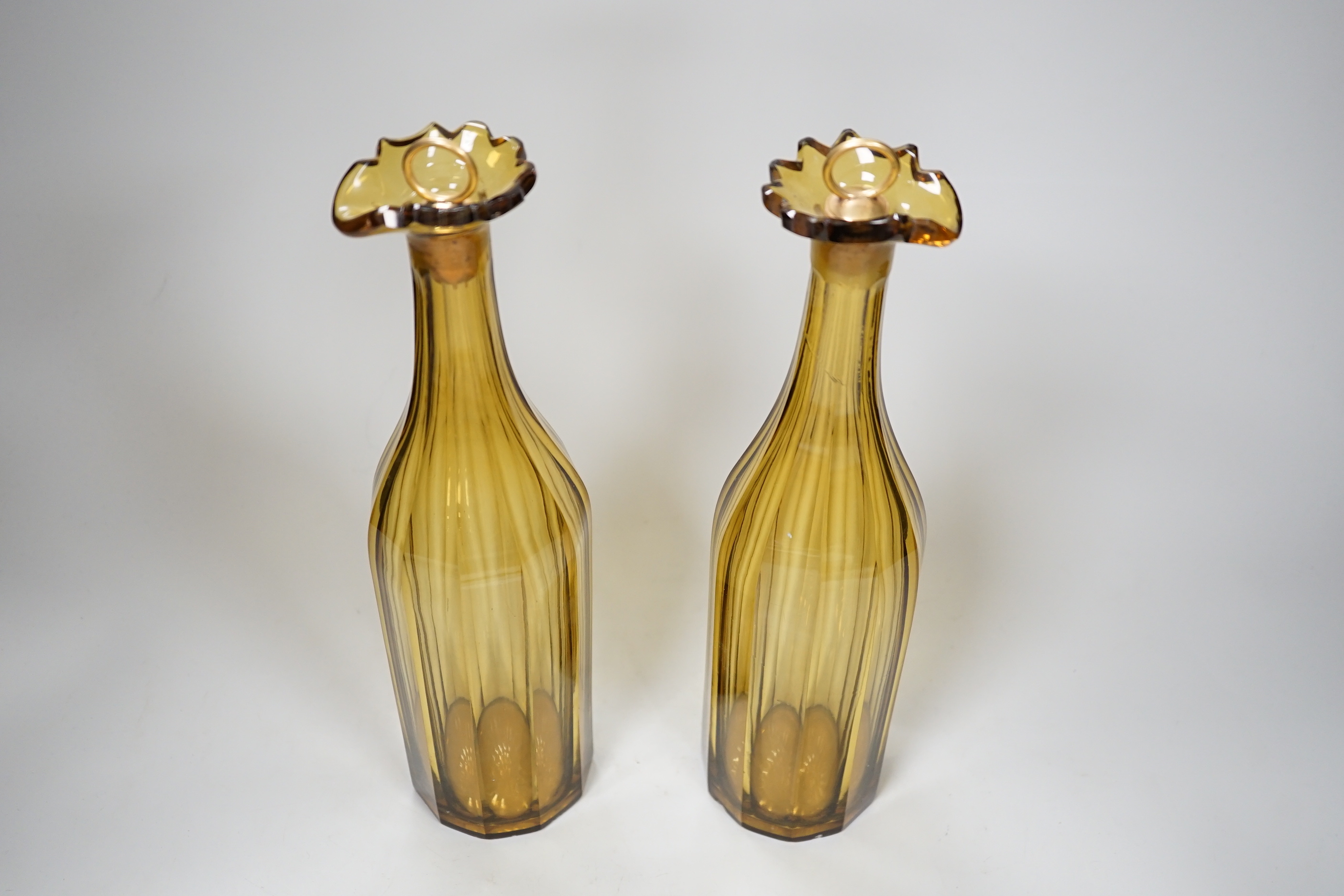 A pair of early 19th century amber panel cut glass decanters, 30cm